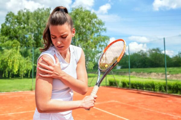 Young female tennis player holding her shoulder in pain, possibly due to tendonitis.