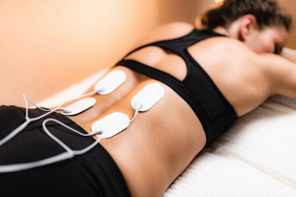 Woman receiving electrical nerve stimulation treatment of her lower back. This may form a part of some pelvic floor physiotherapy treatment sessions.