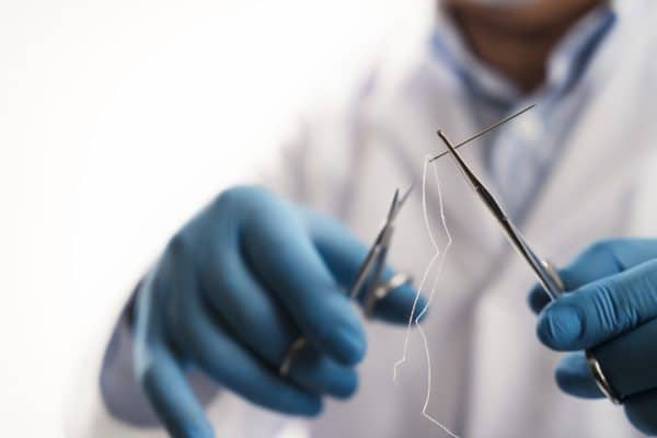 Close up image of a doctor holding scissors and a needle