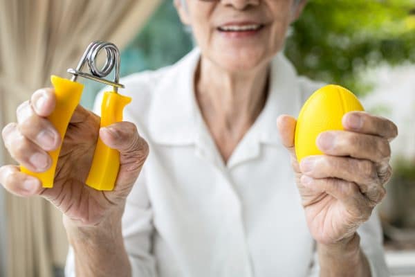 Elderly lady doing finger,palm and wrist exercises with rubber ball & spring hand gripper
