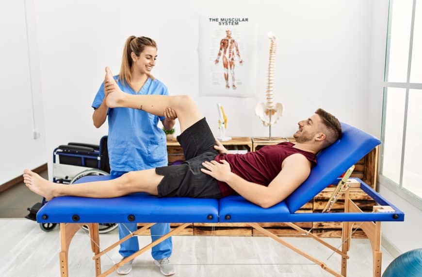 Young female physiotherapist treating male patient on treatment table.