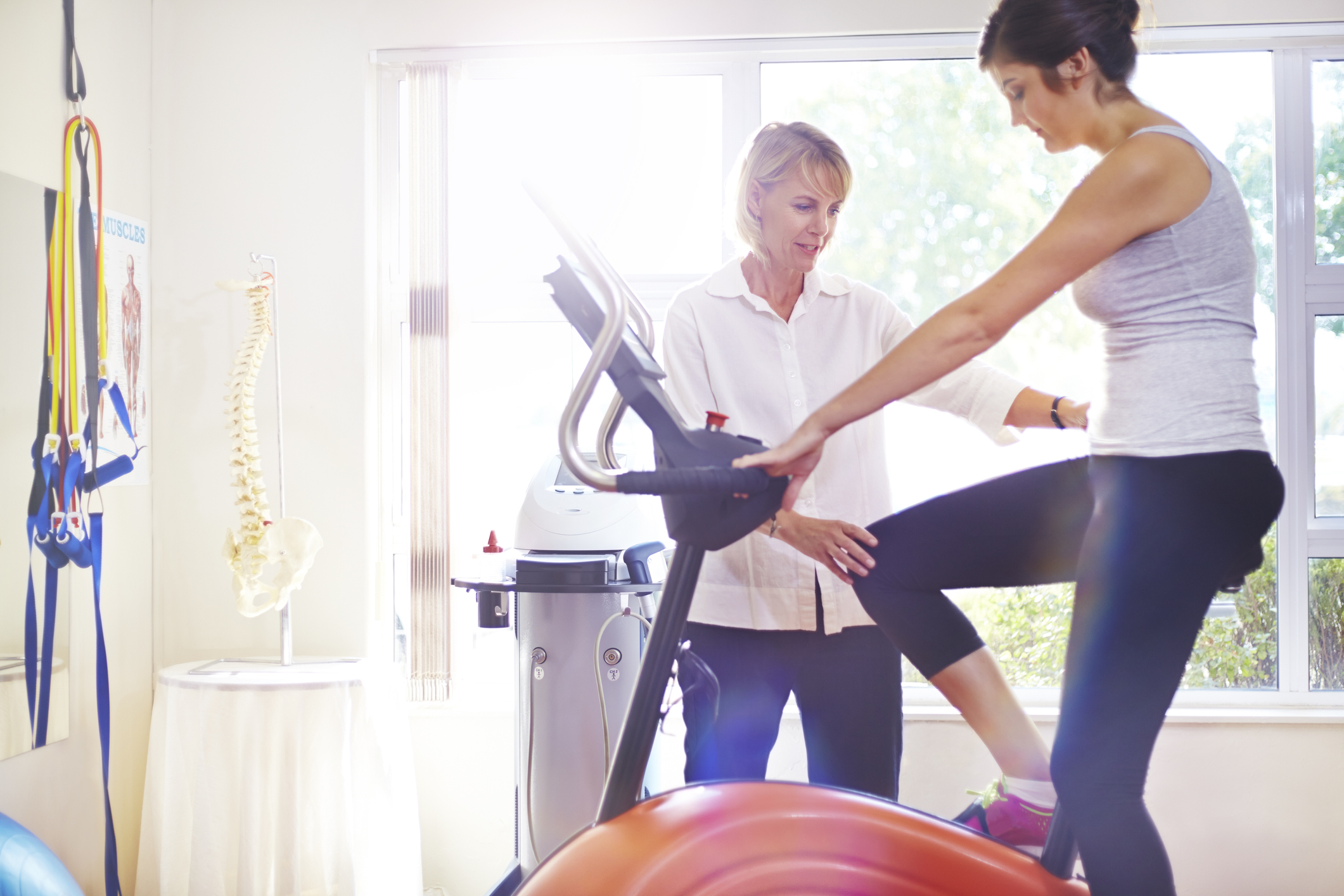 Physical therapist guiding patient on stationary bike